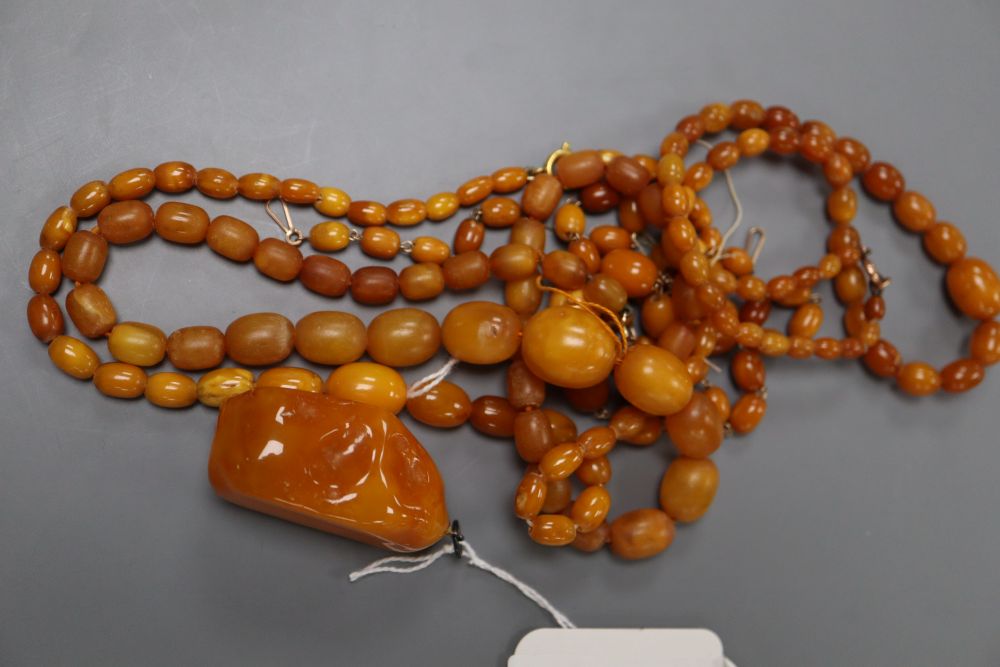 Four assorted amber bead necklaces (1 a.f.) and an amber boulder pendant, gross weight 82 grams.